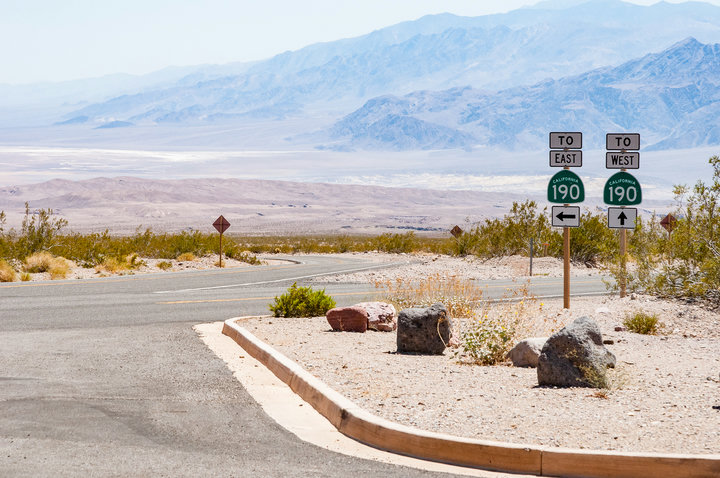 View of Death Valley National Park showing signs pointing to 190 East and West